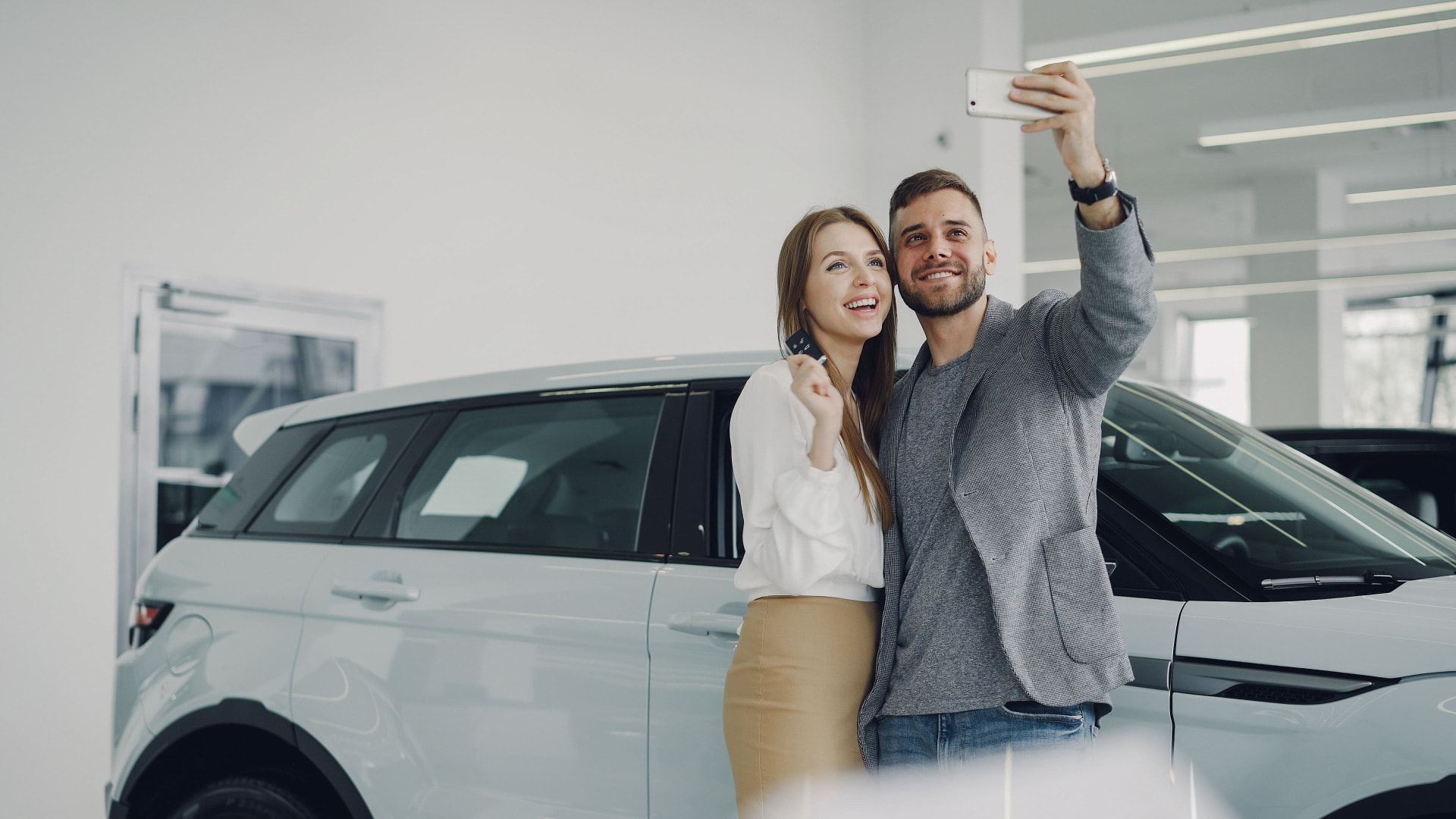 Casal feliz com as chaves do novo carro em concessionária